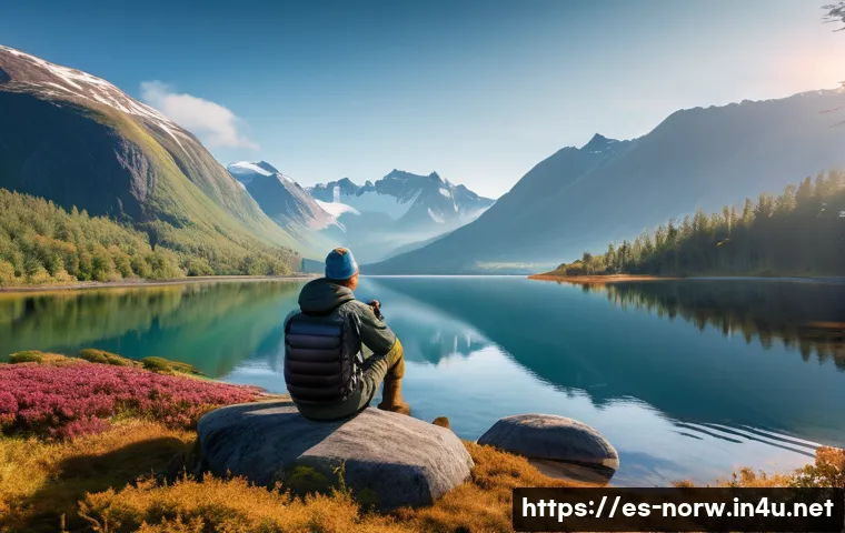 노르웨이에서 가장 아름다운 호수 - A serene Norwegian lake scene at dawn, crystal-clear water reflecting towering snow-capped mountains...
